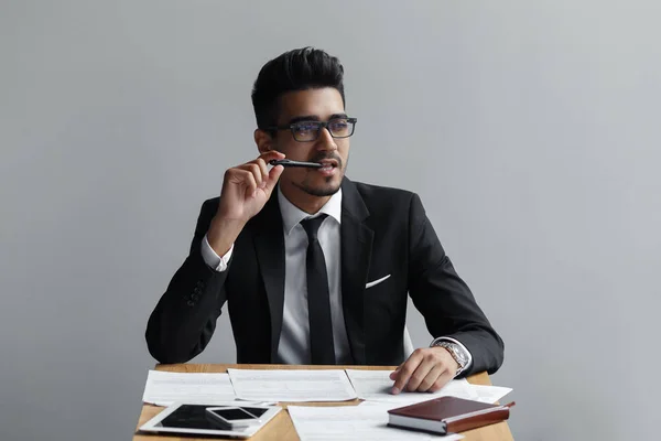 Geschäftsmann mit Stift im Mund auf grauem Hintergrund — Stockfoto