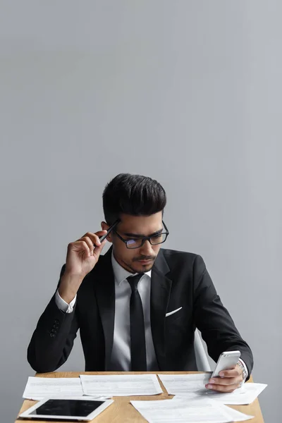 Empresário verificando seu telefone e papéis em sua mesa — Fotografia de Stock