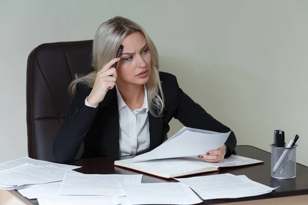 Imagen de la mujer de negocios pensativa con gran bloc de notas en traje sentado a la mesa con documentos — Foto de Stock