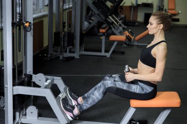 Spor salonunda makinede egzersiz ve kasları - kaslı atletik vücut Fitness modeli esneme genç kadın