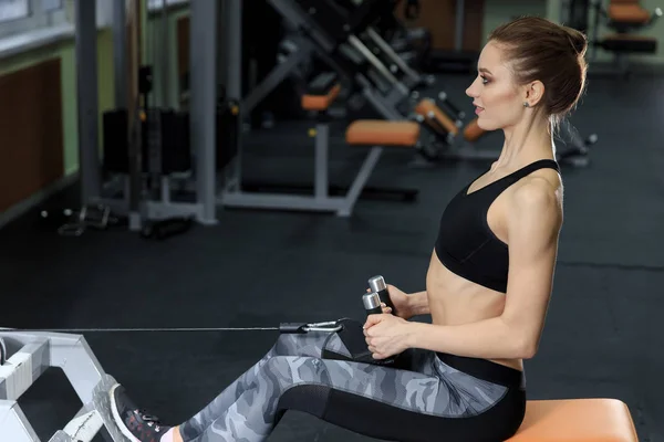 Ung kvinna utövar tillbaka på maskin i gymmet och flexar muskler - muskulös Athletic Bodybuilder Fitness modell — Stockfoto