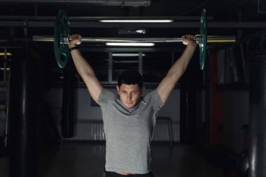 Genç adam bir halter kaldırma spor salonunda.