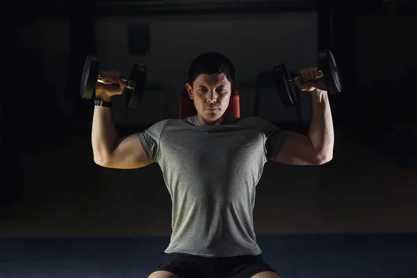Мускулистый человек тренирует плечи гантелями . — стоковое фото
