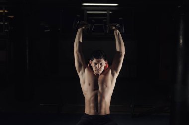 Kaslı adam omuzlarını dumbbells ile eğitim.