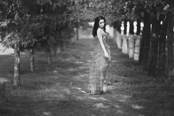 Schönes Mädchen im roten Kleid, das im Park spaziert. — Stockfoto