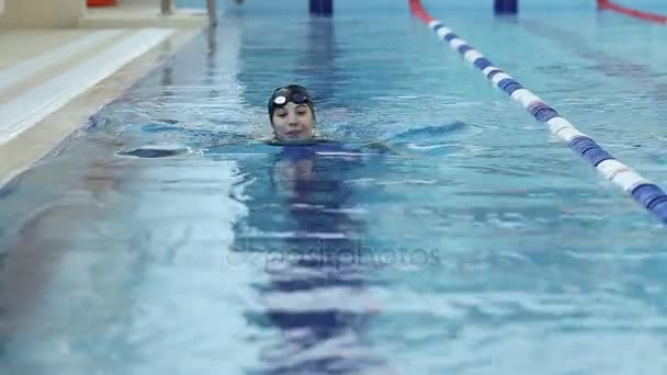 ゴーグルと青い水の屋内レース プールで水泳キャップの若い笑顔の女性. — ストック動画