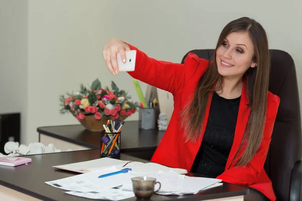 Wanita bisnis muda difoto di smartphone di kantor . — Stok Foto