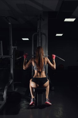 Spor salonunda makinede egzersiz ve kasları - kaslı atletik vücut Fitness modeli esneme genç kadın.