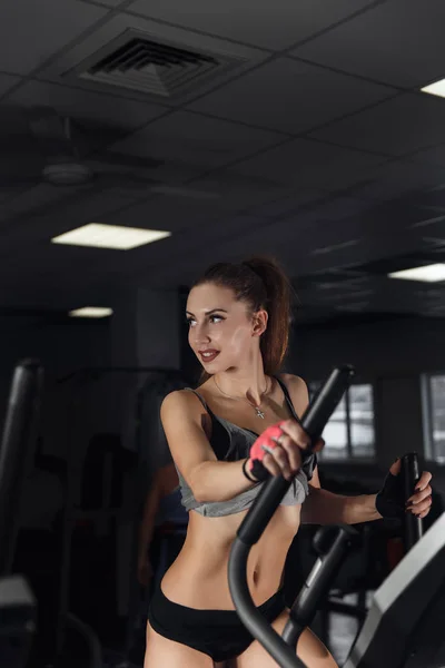 Ung sexig kvinna under träning på cykel på gym. — Stockfoto
