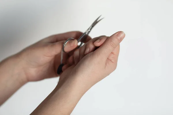 Närbild av en kvinna som klipper naglarna på vit bakgrund. — Stockfoto
