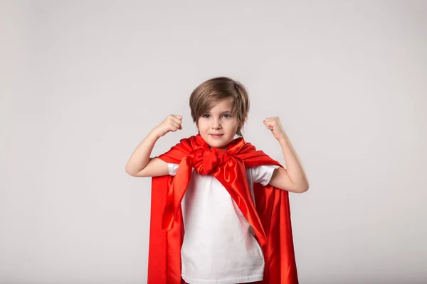 Pequeña chica superhéroe en capa roja muestra su músculo — Foto de Stock