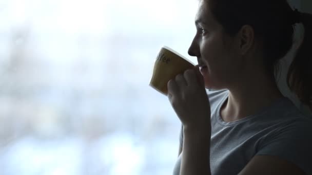 Beauté fille regardant par la fenêtre et appréciant son café ou thé du matin . — Video