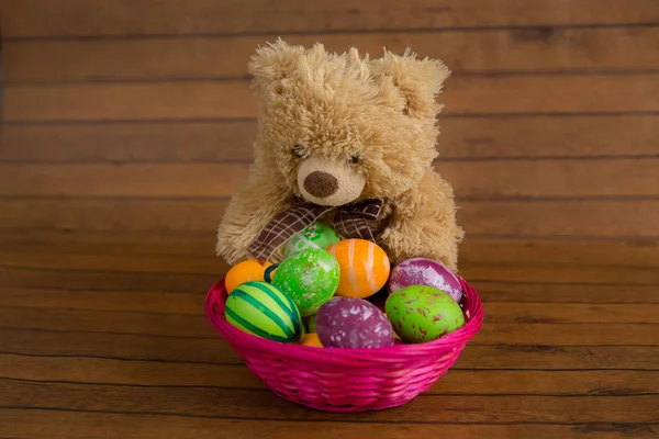 Easter colorful eggs in basket and plush bear