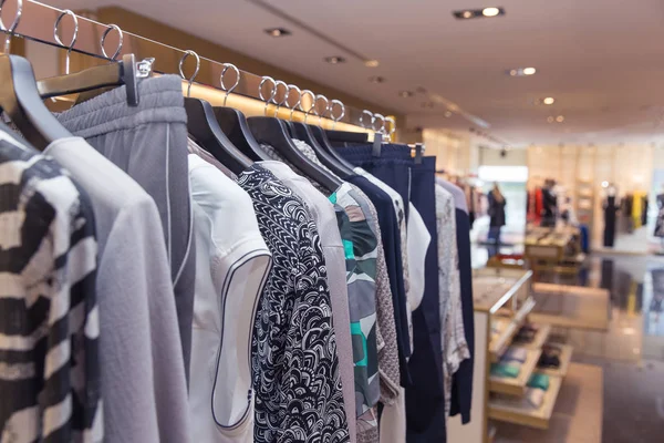 Una fila de ropa colgando de perchas en la tienda — Foto de Stock