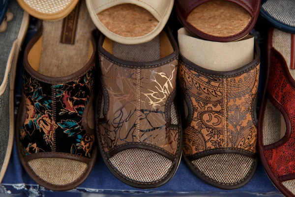 Montón de zapatillas hechas a mano coloridas extendidas sobre una mesa para vender — Foto de Stock