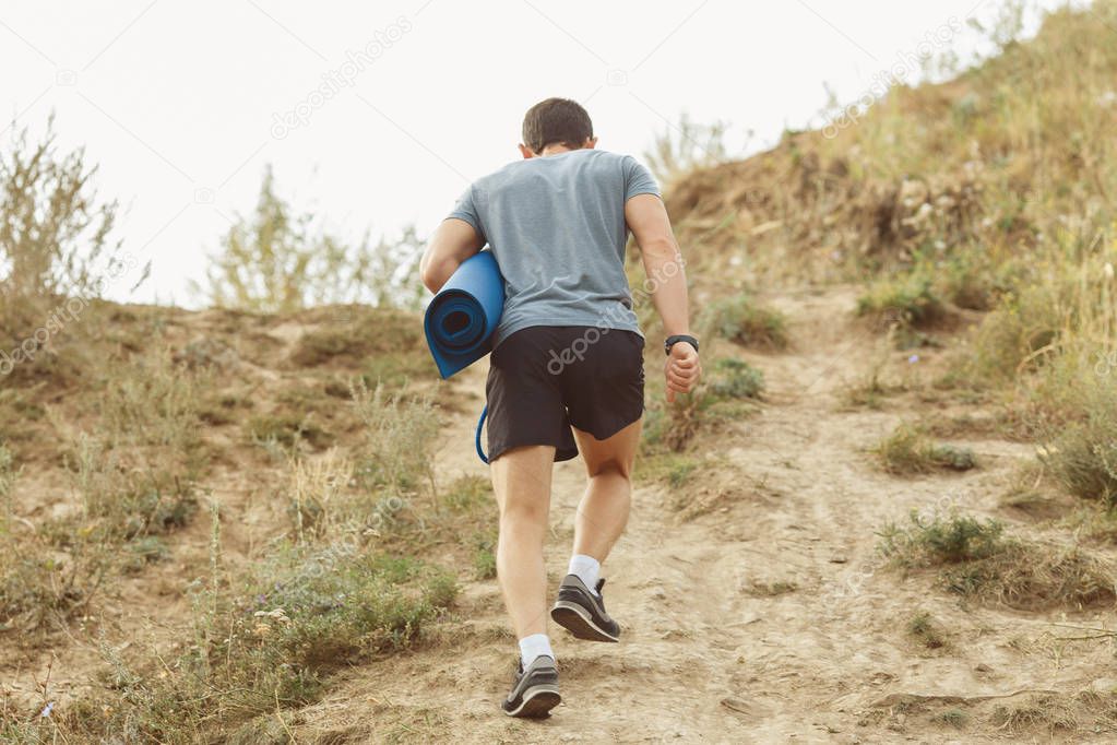 A young man walking on the trail. travel sport lifestyle concept. view from the back.