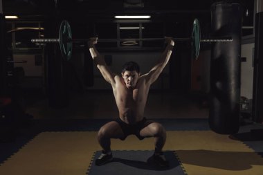 Spor salonunda halter kaldıran kaslı bir adam..