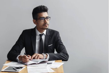 Bir not defteri ve görünüyor uzakta kameradan gri bir arka plan, tablet, telefon ve kağıtları masanın üzerine yazma iş adamı. kopya alanı.