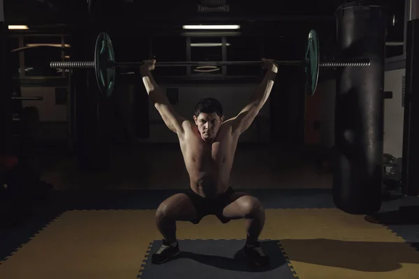 Мускулистый человек в спортзале, поднимающий штангу. — стоковое фото
