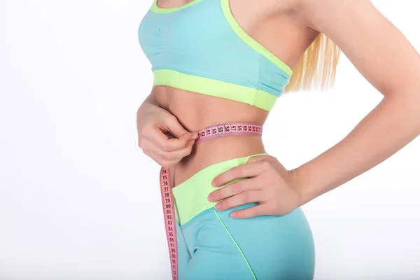Chica fitness midiendo su cintura con cinta métrica sobre fondo blanco . —  Fotos de Stock