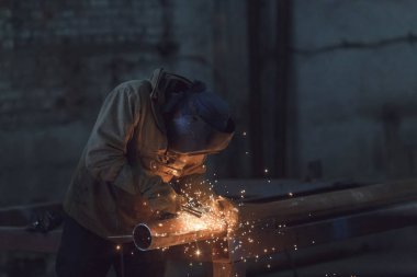 worker welding metal with sparks at factory. clipart