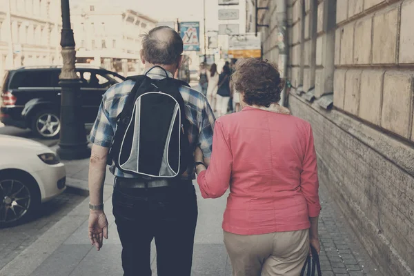 Achteraanzicht van bejaarde echtpaar wandelen in de stad — Stockfoto