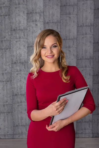 Bella giovane donna in abito rosso. Hostess con tablet in mano — Foto Stock