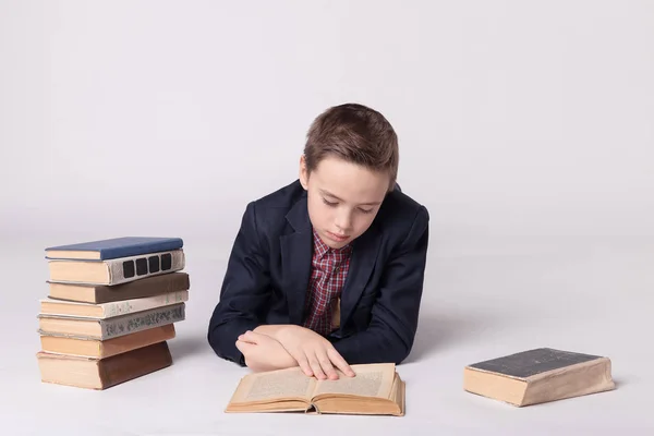 Netter Junge im Anzug lügt und liest ein Buch auf weißem Hintergrund — Stockfoto