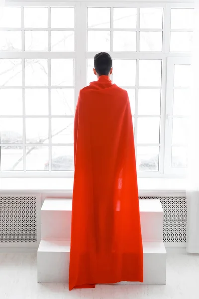El hombre de negocios con capa roja de superhéroe está de espaldas a la cámara. Joven con traje y capa de superman — Foto de Stock