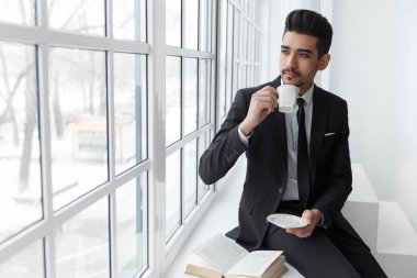 Pencere ve içki kahve üzerinde oturan işadamı