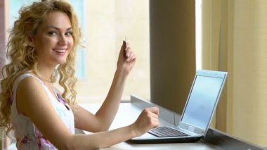 Kredi kartı elinde tutan ve laptop klavye kullanarak güvenlik kodunu girerek güzel kadın