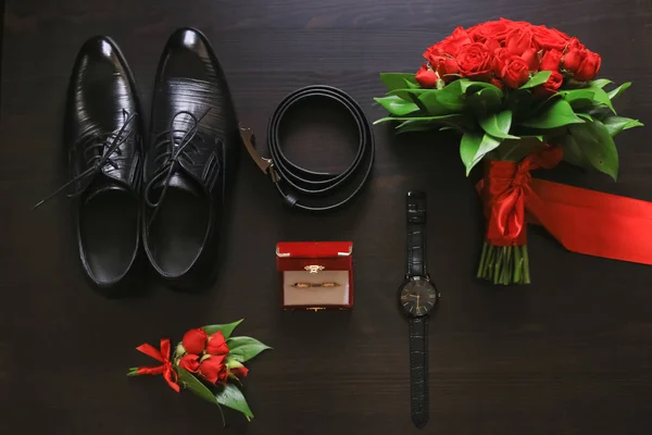 Detalles de la boda. Accesorios de novio. Zapatos, anillos, cinturón, boutonniere y reloj en la mesa . — Foto de Stock