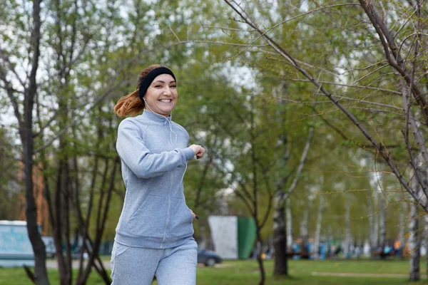 Спортивная девочка бегает в парке и слушает музыку — стоковое фото