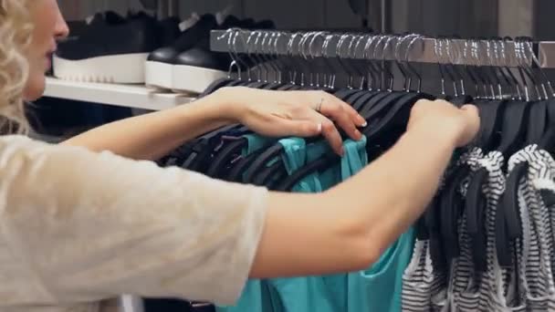 Compras, moda, estilo e conceito de pessoas. Compras mulheres escolhendo vestido em shopping ou loja de roupas — Vídeo de Stock