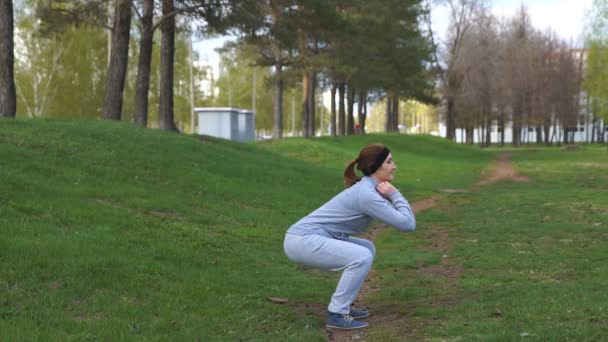 Young beauty girl do exercises at the park — Stock Video