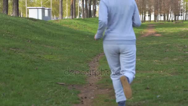 Uma mulher a correr no parque. Modelo de fitness desportivo bonito durante o treino ao ar livre . — Vídeo de Stock