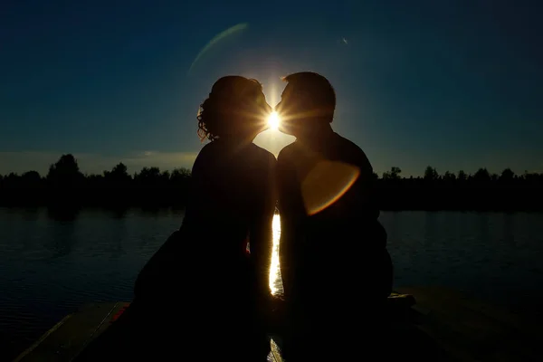 Pareja enamorada silueta de contraluz en el lago. Silueta de pareja besándose al atardecer — Foto de Stock
