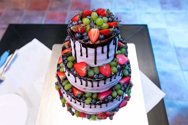 Three parts naked wedding cake with fruits and berries