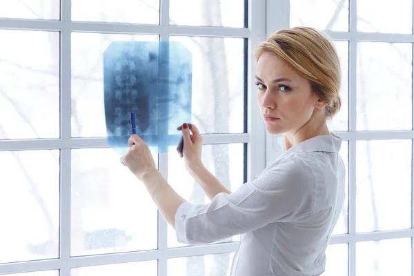 Молодая врач женщина указывает на рентген — стоковое фото
