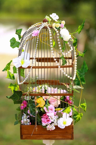 Floral arrangement of flowers, bird cage with flowers Stock Photo