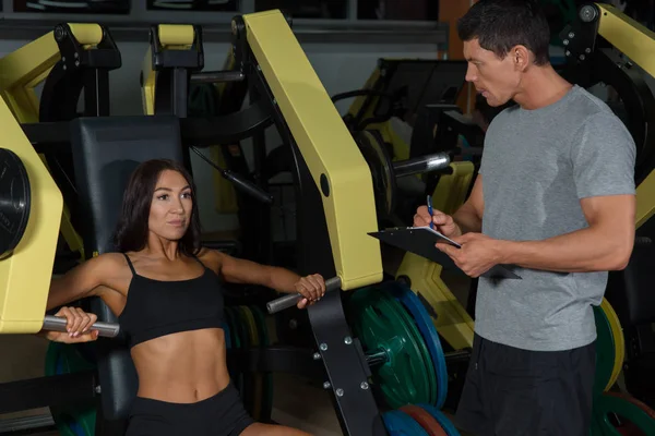 Kadın workuot egzersiz makinede eğitmen ile