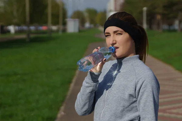 Красивая молодая женщина держит бутылку воды после тренировки в парке . — стоковое фото