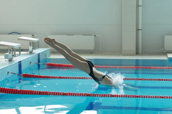 Jeune fille nageuse, qui saute et plonge dans la piscine sportive intérieure . — Photo