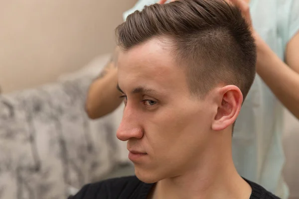 Nowa fryzura na mecie. Widok z boku młody człowiek coraz zadbana fryzjerka, siedząc w fotelu na fryzjera — Zdjęcie stockowe