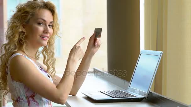 Hermosa mujer con tarjeta de crédito en la mano y muestra su dedo en la tarjeta de crédito — Vídeos de Stock