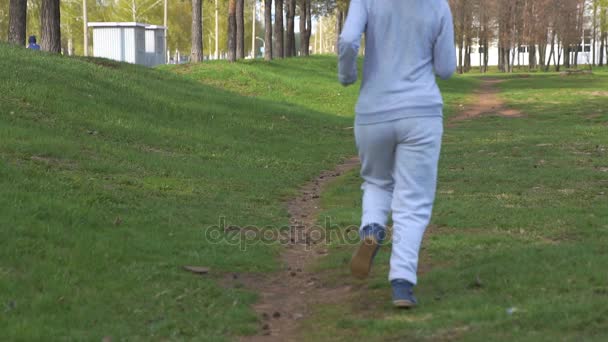 Kvinna löpare kör i park i slow motion. Vackra sportig fitness modell under utomhus träning. — Stockvideo