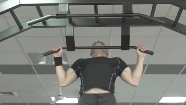Sportoló izmos fitness férfi modell húzza fel a vízszintes rúd egy edzőteremben. — Stock videók