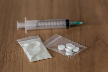kaşık, plastik paket kokain ve ahşap masa üzerinde şırınga ile.
