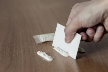 Plastik paket, çizgiler ve ahşap masa üzerinde kokain yığını.