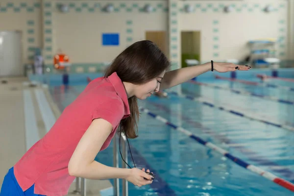 Formatrice femme tenant un chronomètre au bord de la piscine et effectue de la formation — Photo